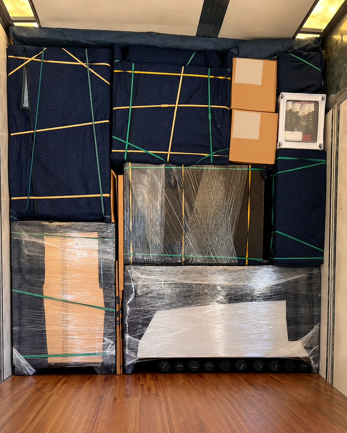 Household belongings padded, wrapped, and secured inside a moving trailer.
